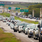 Congested highway traffic with school bus visible among cars and trucks in multiple lanes
