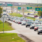 Heavy daytime traffic on Highway 290 with toll road signage and overpass infrastructure visible