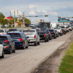 Single-lane traffic backup with overhead traffic signals and commercial buildings