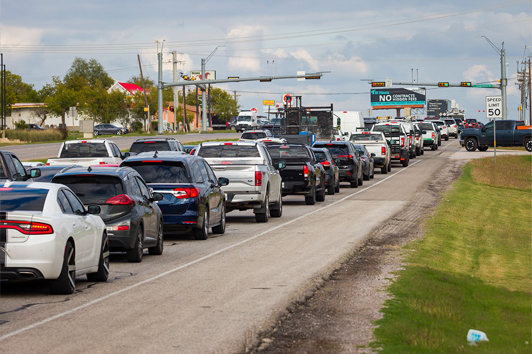 Single-lane traffic backup with overhead traffic signals and commercial buildings