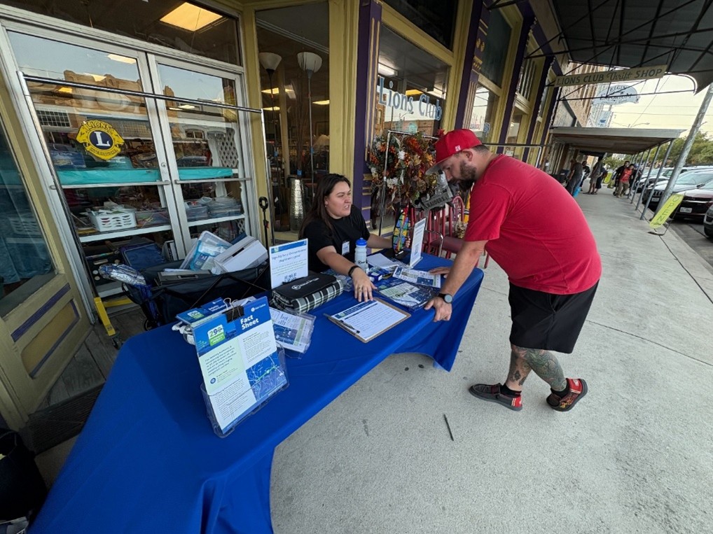 A 290 Extension Project team providing information to a member of the public at a table outside the Lions Club.